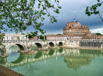 Arch bridge over lake against buildings