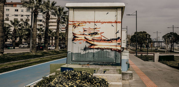 Graffiti on building by trees in city against sky