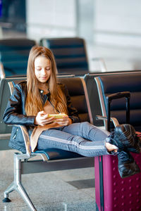 Girl using mobile phone while sitting at airport