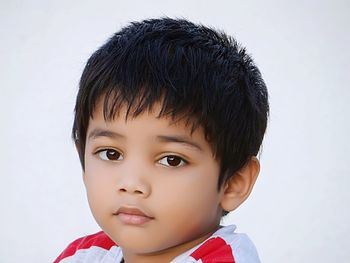 Close-up portrait of boy standing against white wall