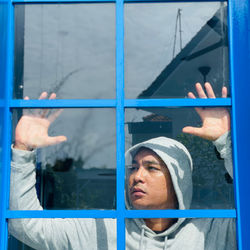 Portrait of man looking through window in building