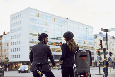 Rear view of business coworkers with bicycles on street in city