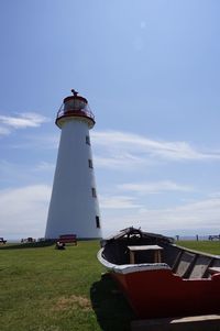 Lighthouse by road amidst buildings against sky