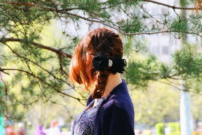 Side view of woman with braided hair standing at park