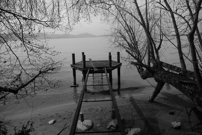 Empty chairs and bare trees against sky