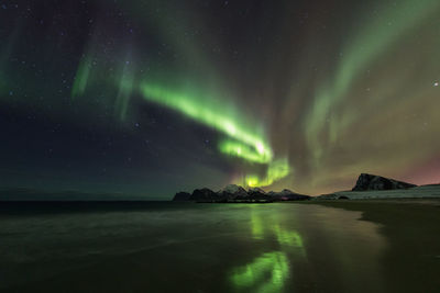 Scenic view of beach against aurora borealis at night