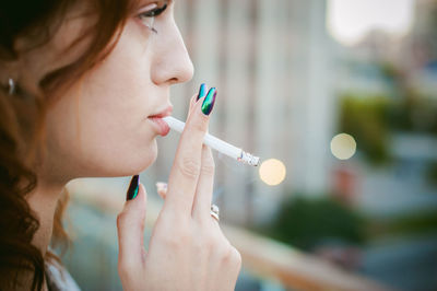 Close-up of woman smoking cigarette in city