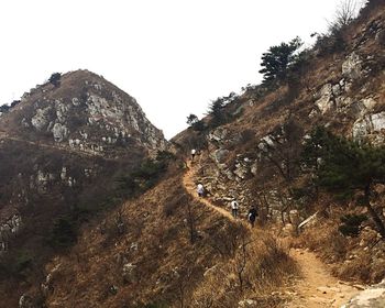 People on mountain against clear sky