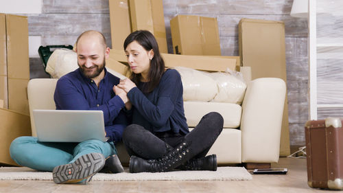 Young woman using laptop while sitting on sofa at home