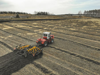 High angle view of tractor and agricultural equipment on field against sky