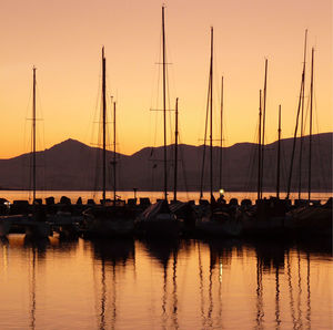 Silhouette of boats in lake at sunset