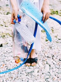 Low section of woman holding hands on pebbles