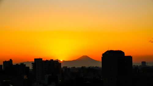 Silhouette buildings against orange sky