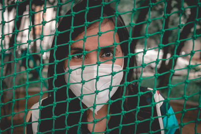 Close-up portrait of a girl behind fence