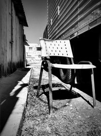 Empty chairs on footpath by abandoned building