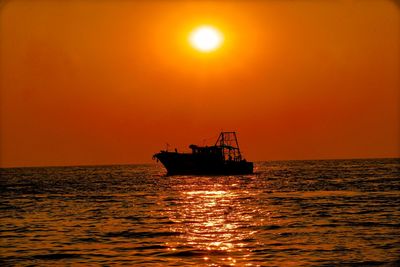 Silhouette boat in sea against sky during sunset