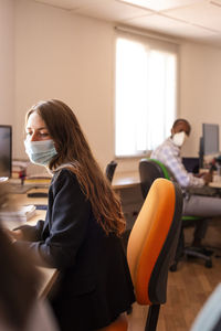 Businesswoman in protective face mask working at desk in office