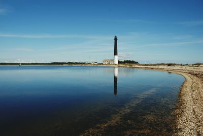 Lighthouse by sea against sky