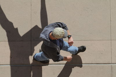 High angle view of man checking time while walking on footpath