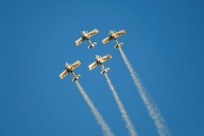 Low angle view of airshow against clear blue sky