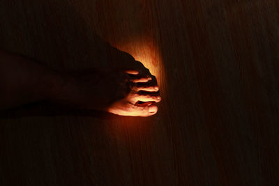 Close-up of person hand on illuminated wood