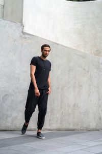 Full length portrait of young man standing against wall