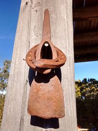 Close-up of rusty hanging on wood against sky