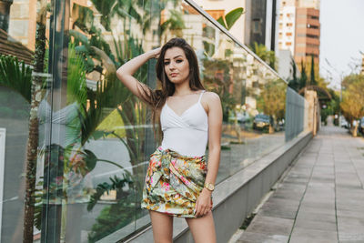 Portrait of beautiful young woman standing against wall