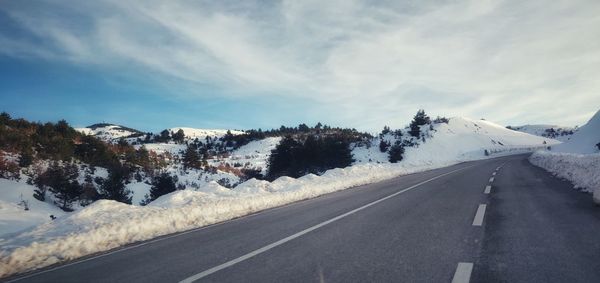 Road amidst snowcapped mountains against sky