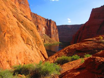 Scenic view of cliff by river against sky