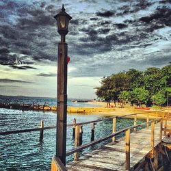 Pier on sea against cloudy sky