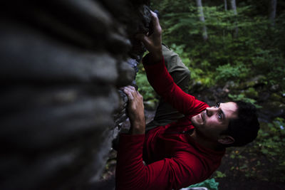 High angle view of serious man climbing on rock in forest