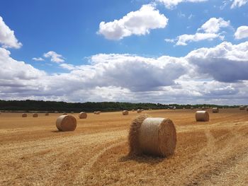 Hay bales on field against sky