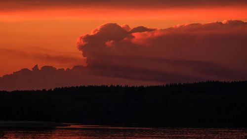 Scenic view of lake by silhouette trees against romantic sky at sunset