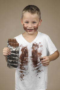 Portrait of smiling boy standing against gray background