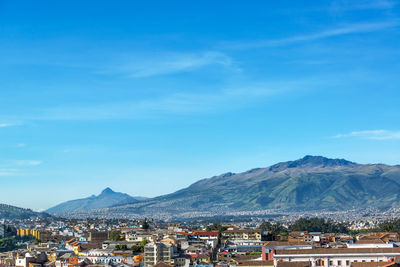 Cityscape by mountains against sky