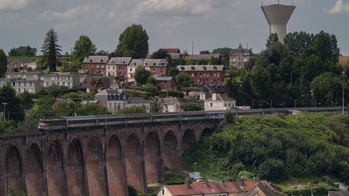 Train on railway bridge against sky at barentin