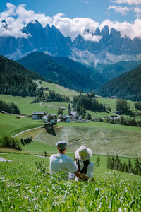 Rear view of people walking on field against mountains