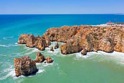 Panoramic view of rocks and sea against blue sky