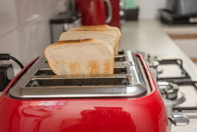 Close-up of breads in toaster by wall at kitchen