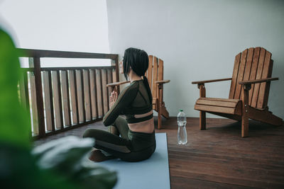 Rear view of woman sitting on chair at home