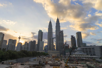 Petronas towers and skyscrapers against sky during sunset