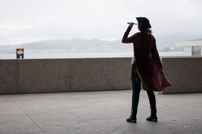 Rear view of woman photographing with umbrella standing in city