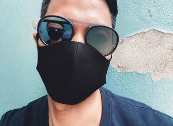 Midsection of man wearing sunglasses against wall