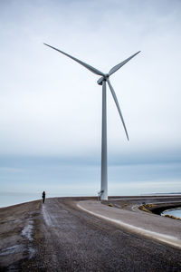 Windmill by sea against sky