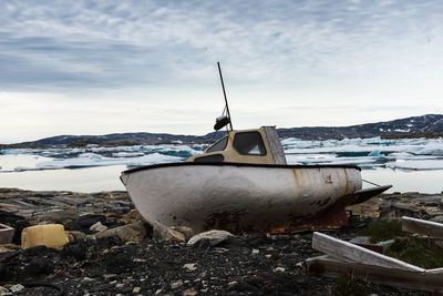 Abandoned boat on snow against sky