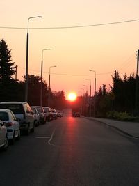 Cars on road against sky at sunset