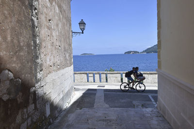 Bicycle on wall by sea against clear sky