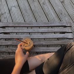 Midsection of woman holding drink in jar while sitting on floor