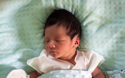 Baby sleeping on turquoise mattress